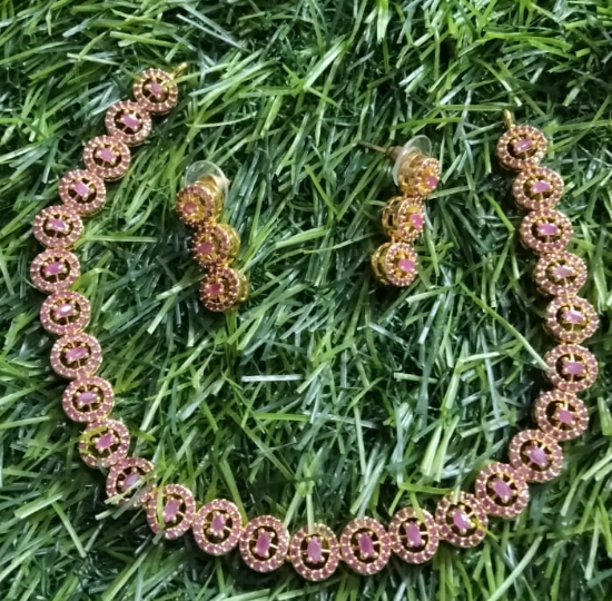 బంగారు పూత పూసిన లోహం మరియు కెంపులు లేదా గులాబీ వజ్రాలను పోలి ఉండే చిన్న, గుండ్రని, గులాబీ రాళ్లతో కూడిన చెవిపోగులు యొక్క చిత్రం